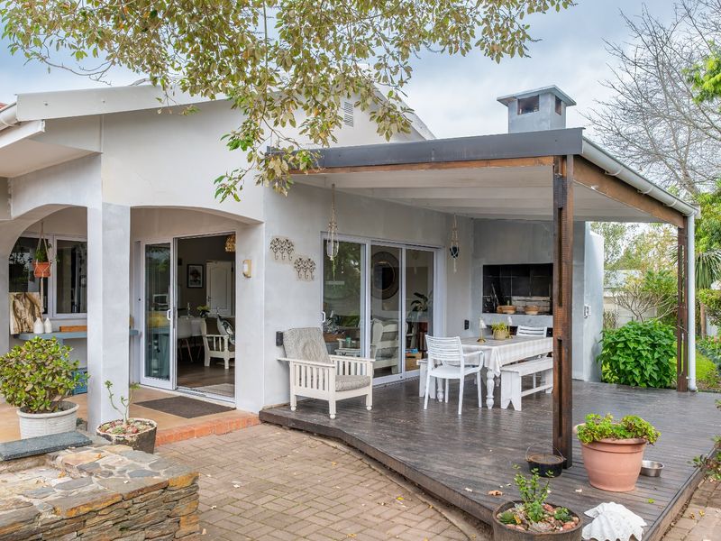 Covered outdoor patio featuring timber decking, a built-in braai, and direct access to the interior living space through sliding glass doors.