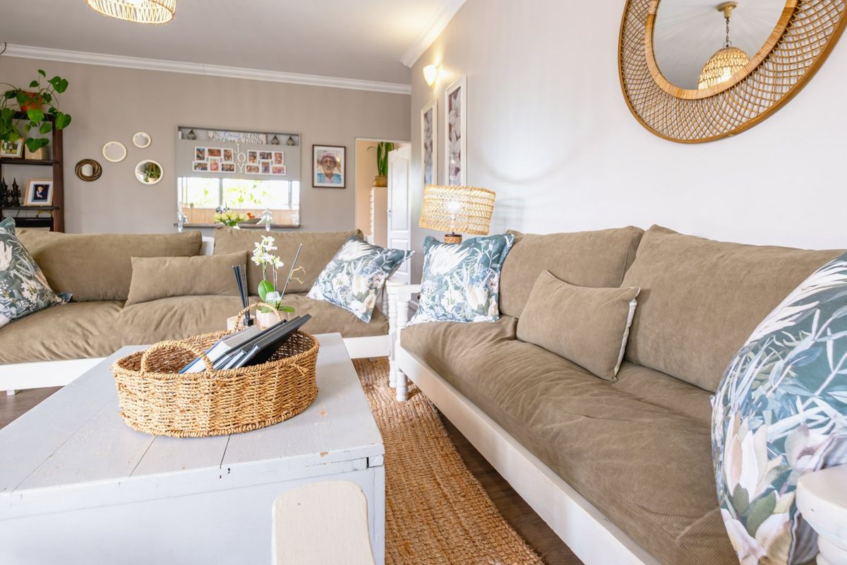 A bright and inviting living room featuring neutral wall tones, cove cornicing, and durable laminate flooring, creating a comfortable and well-maintained living space.