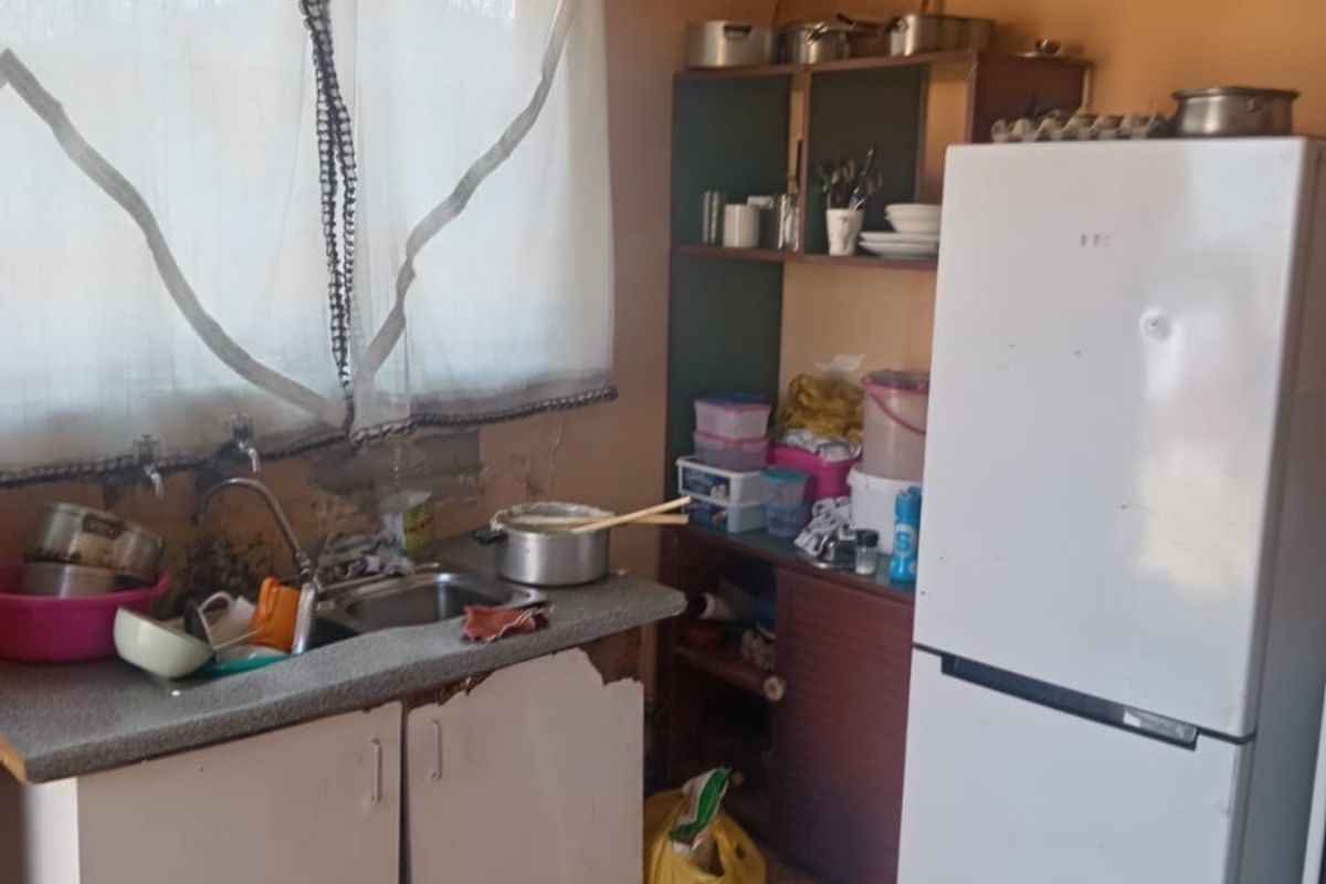 A dated kitchen area featuring a stainless steel sink, laminate countertops, and built-in cabinetry, requiring significant renovation and cosmetic updates to improve functionality and aesthetics.