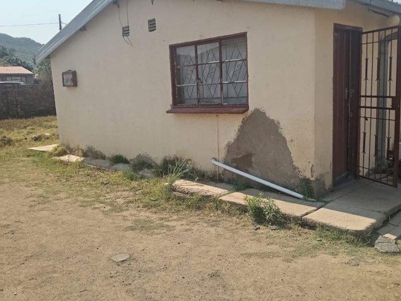 Exterior view of a small commercial building showing significant plaster damage and peeling paint on the exterior wall.