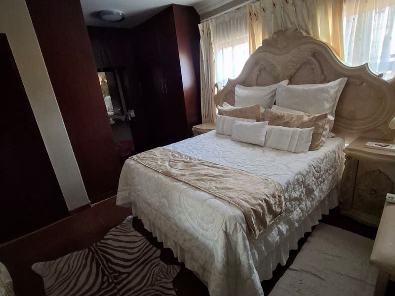 A bedroom featuring dark wood built-in cupboards, decorative ceiling cornicing, and flush mount lighting fixtures.