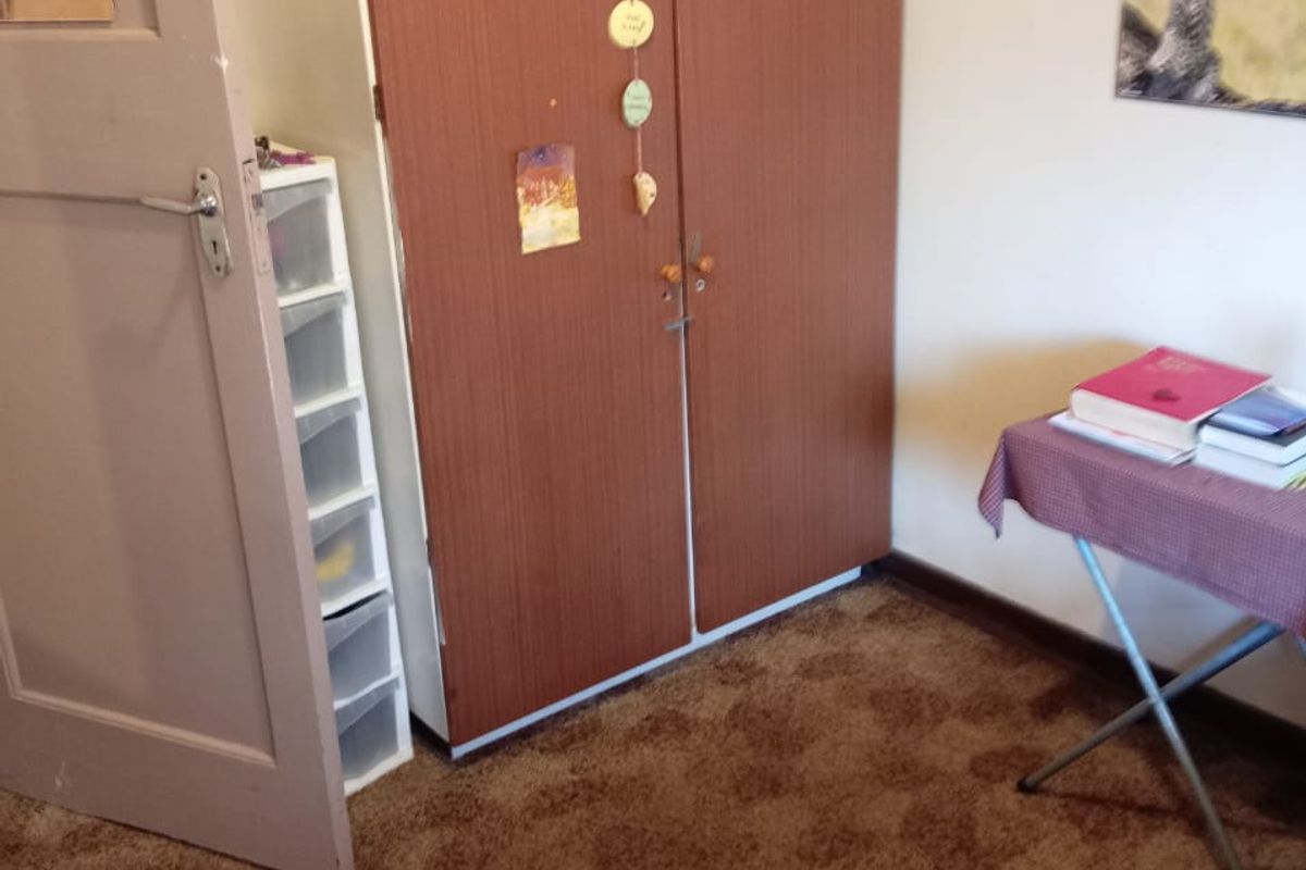 A bedroom featuring a built-in wooden wardrobe and brown carpeting.