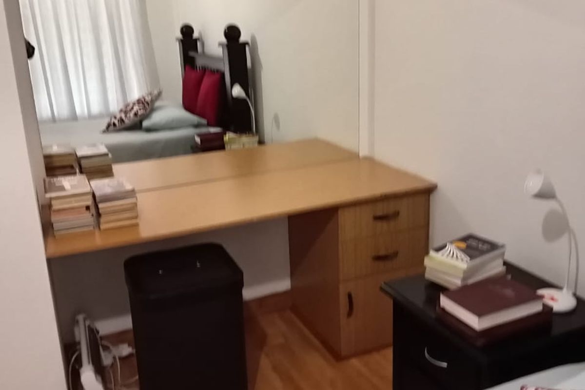 A bedroom featuring a built-in vanity unit with a large wall-mounted mirror and laminate flooring.