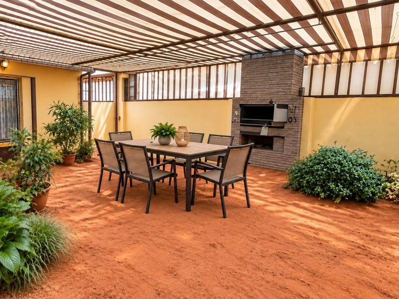 Covered outdoor patio area featuring a built-in brick braai, striped canopy roofing, and ample space for outdoor dining.