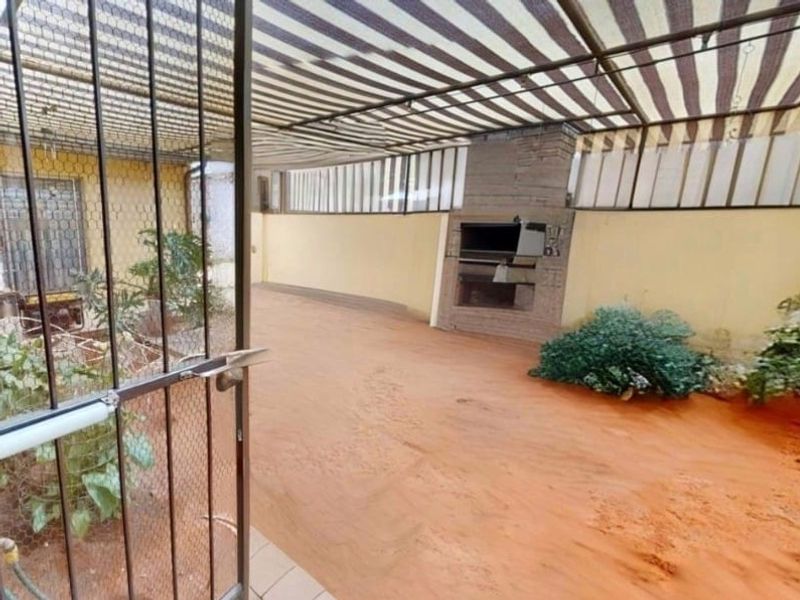 Covered outdoor patio area featuring a built-in braai and tiled flooring, providing a functional space for outdoor entertaining.