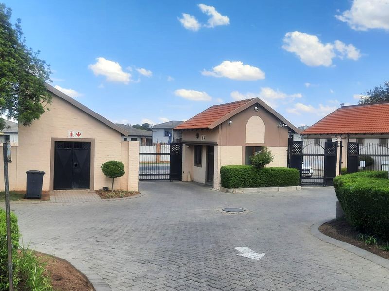The secure entrance to the apartment complex features a paved driveway, gated access, and a dedicated guard house.