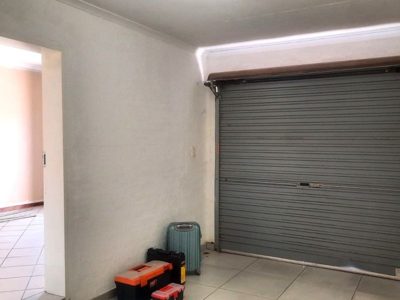 A functional garage space featuring a secure roller shutter door and tiled flooring, providing direct access to the interior of the apartment.