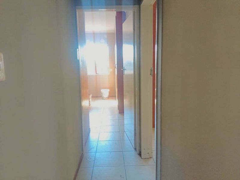A view through a hallway leading into a bathroom area with tiled flooring.