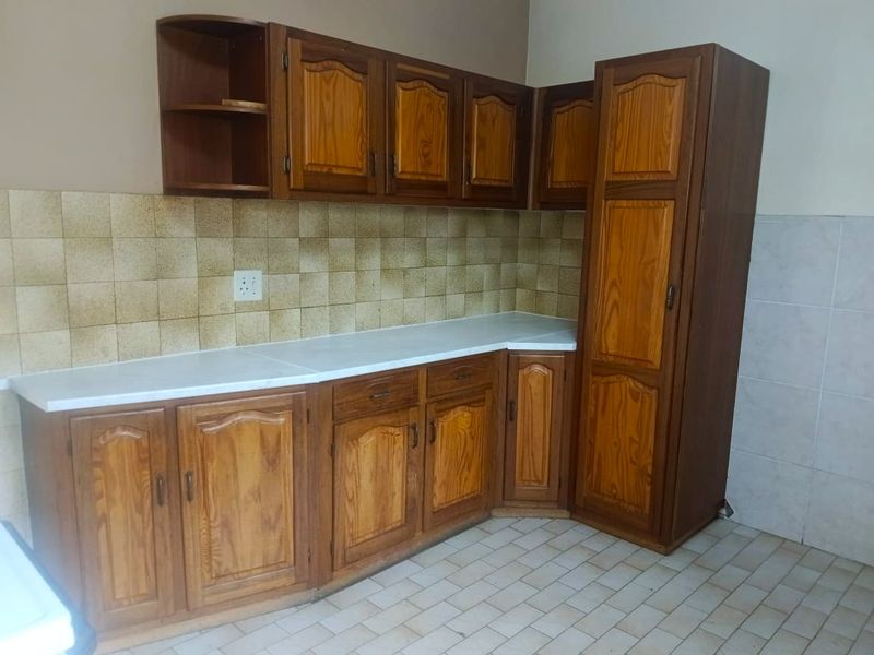A dated kitchen featuring traditional wood-look cabinetry, laminate countertops, and tiled backsplash, offering a functional layout ready for modern updates.