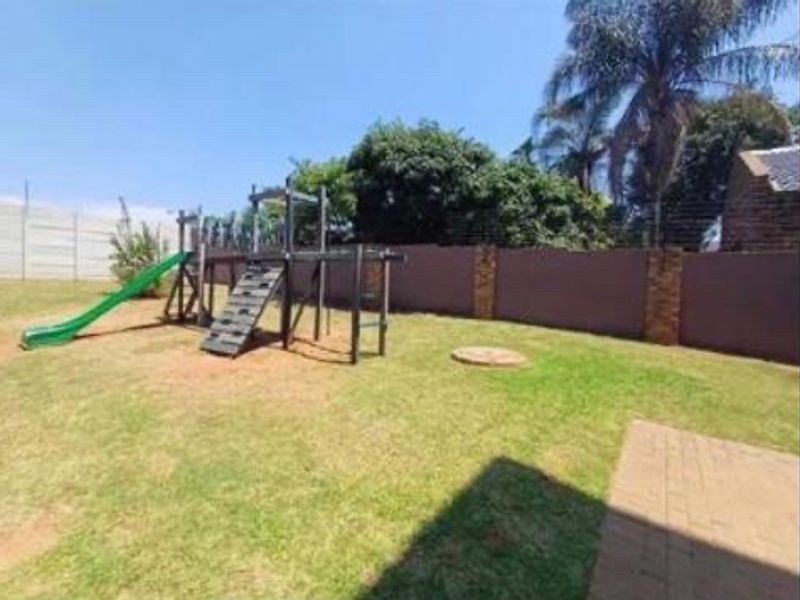 A private backyard garden featuring a lawn, paved area, and perimeter walling.
