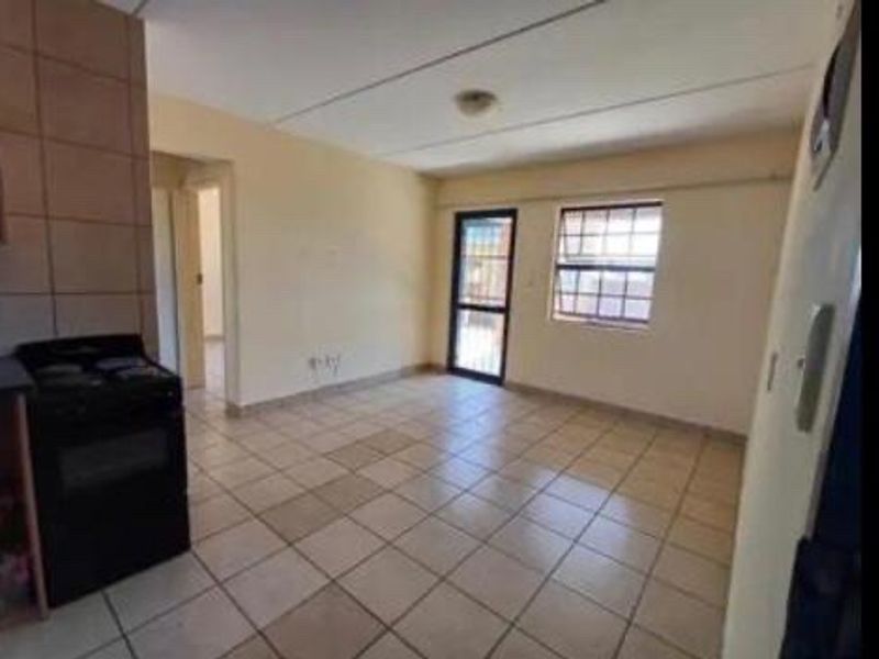 Open plan living area featuring tiled flooring, a freestanding stove, and access to an exterior door with security gate.