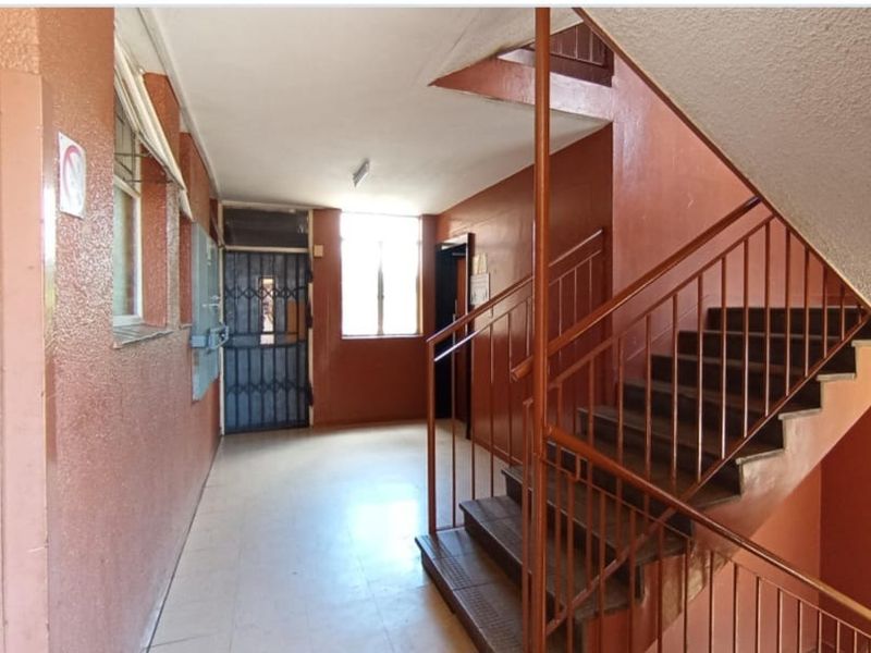Communal apartment hallway featuring a staircase with metal balustrades, tiled flooring, and a security gate entrance.