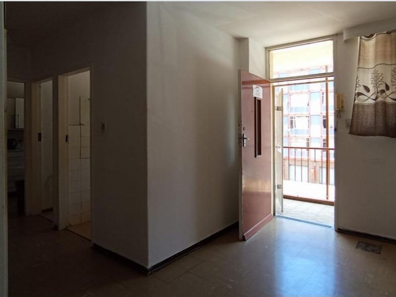 An empty entrance area featuring tiled flooring, an intercom system, and direct access to an outdoor balcony.