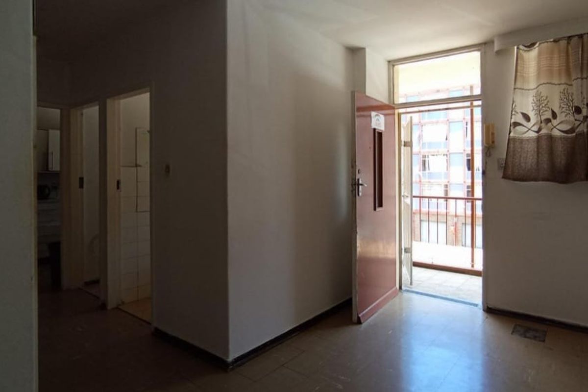 An empty living area featuring tiled flooring and direct access to a balcony, providing a blank canvas for renovation.