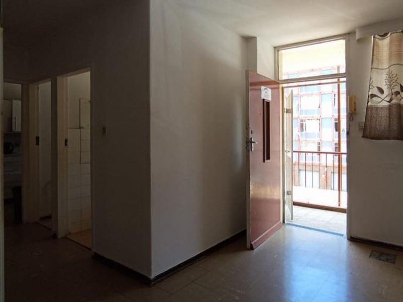 An empty living area featuring tiled flooring and direct access to a balcony, providing a blank canvas for renovation.