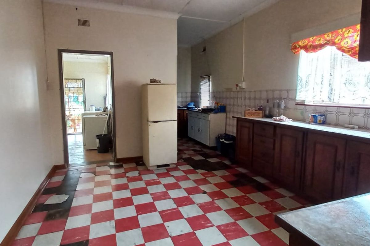 A dated kitchen featuring traditional wooden cabinetry, a tiled backsplash, and a distinctive checkerboard floor, offering significant potential for a modern renovation.