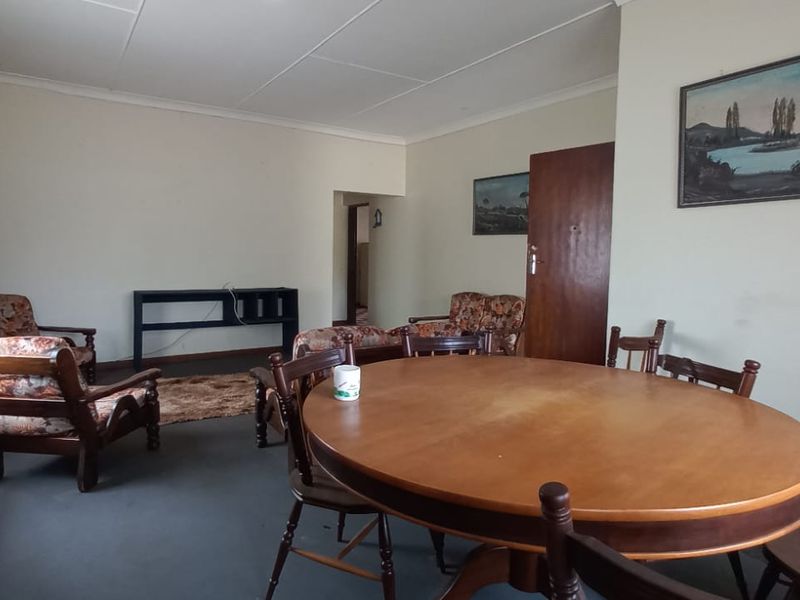 A spacious living and dining area featuring neutral walls, coved ceilings, and a traditional layout suitable for modern updates.