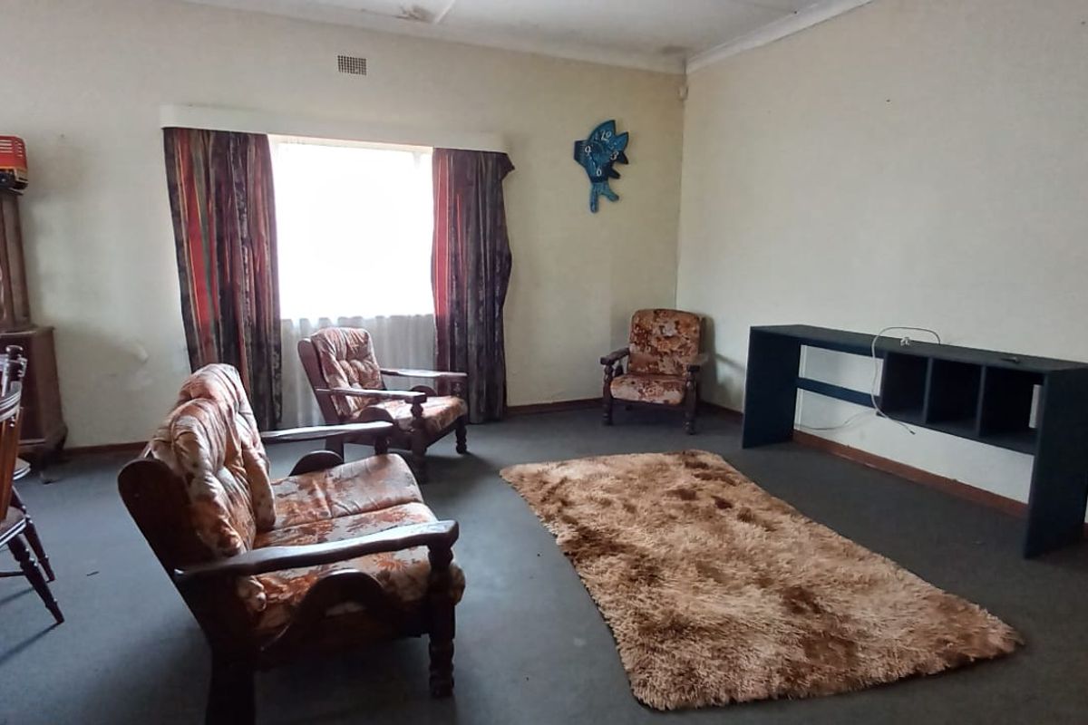 A living room featuring dated carpet and visible ceiling water staining, offering a blank canvas for renovation and modernization.