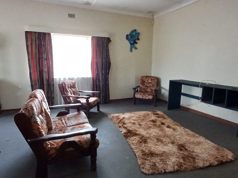 A living room featuring dated carpet and visible ceiling water staining, offering a blank canvas for renovation and modernization.