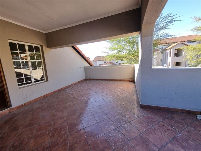 A covered balcony featuring tiled flooring and plastered walls, offering an open outdoor space suitable for relaxation.