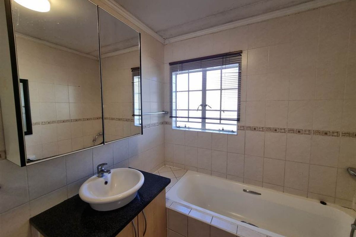 A functional bathroom featuring a vanity with a vessel sink, a medicine cabinet, and a built-in bathtub with tiled wall surrounds.