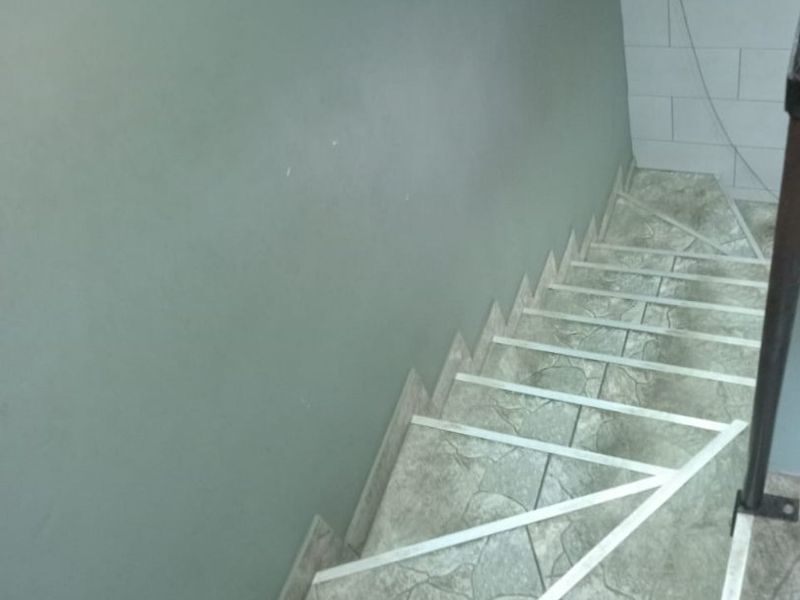 A staircase featuring tiled steps with metal nosing and partial wall tiling, showing signs of wear and tear.