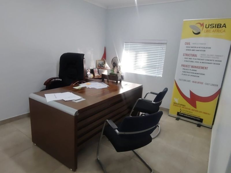 A functional office space featuring tiled flooring and venetian blinds, suitable for a professional home workspace.