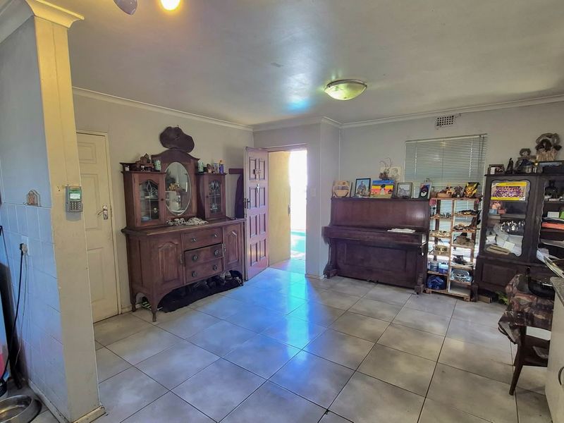 Open plan living area featuring tiled flooring, kitchen cabinetry with granite countertops, and direct access to the exterior through a security gate.
