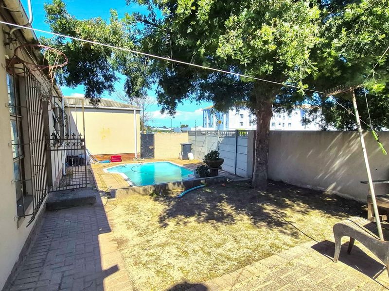 Rear garden area featuring a swimming pool, paved patio space, and perimeter boundary walls with security features.
