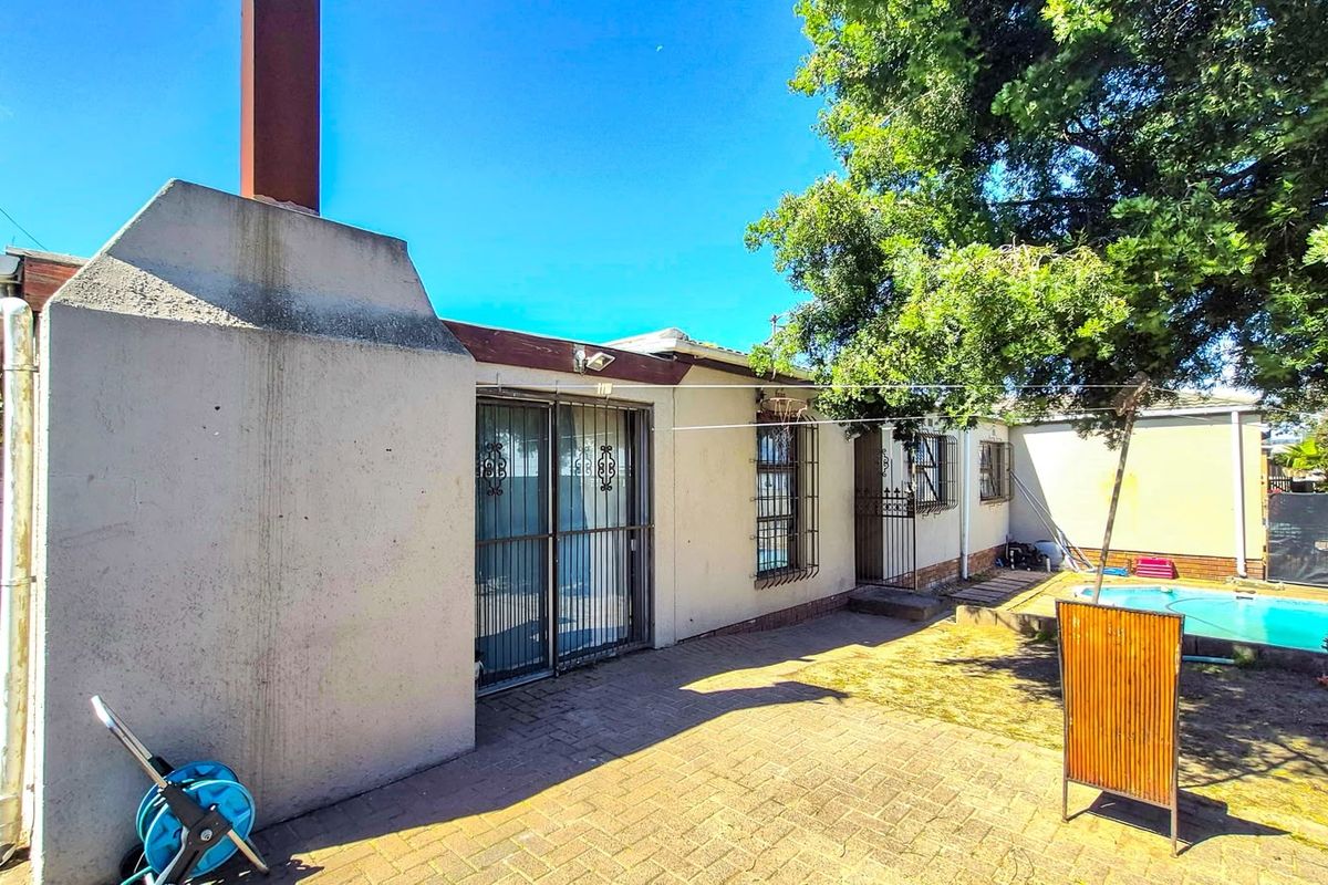 Rear exterior view of the property featuring a paved patio area, a swimming pool, and a prominent chimney stack.