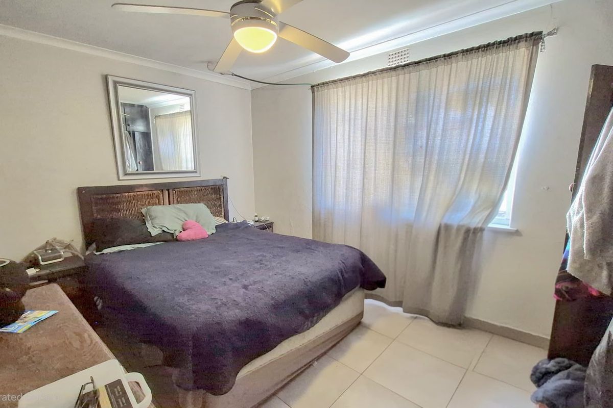 A functional bedroom featuring tiled flooring, a ceiling fan, and a window with curtains, providing a neutral base for personalization.