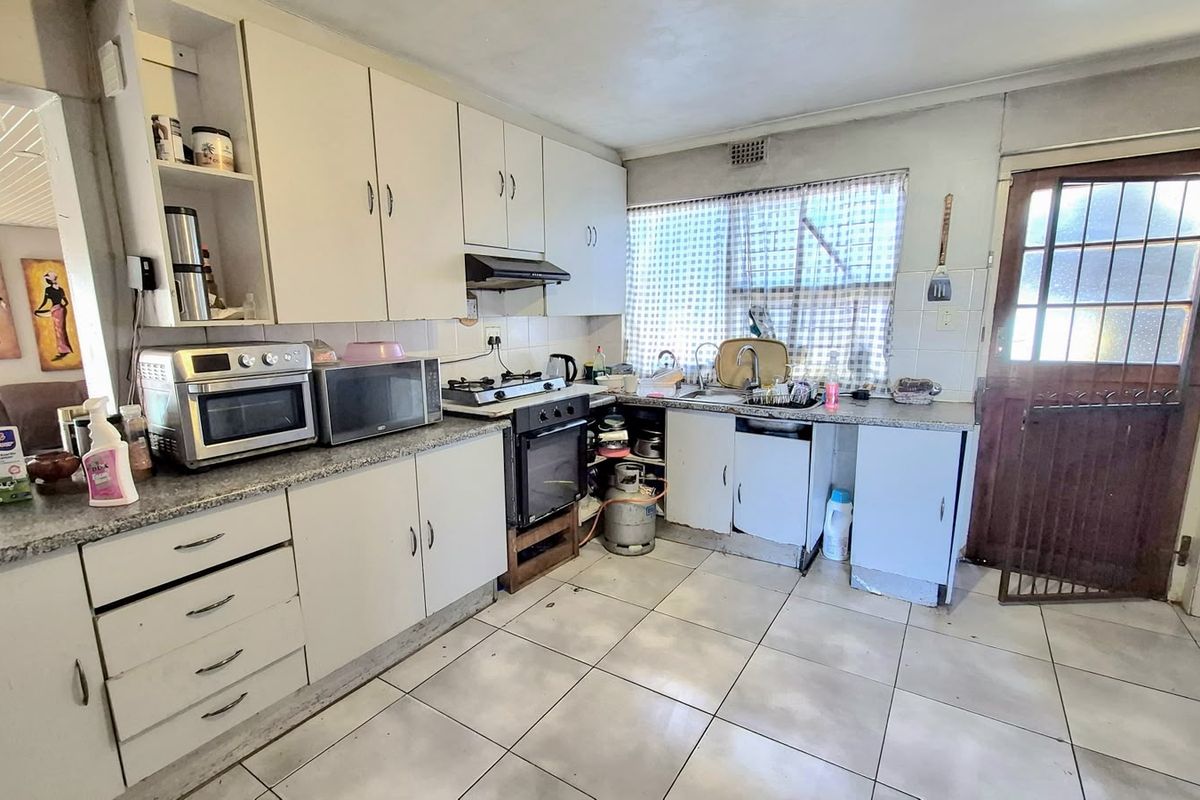 A functional kitchen featuring built-in cabinetry, a gas stove with oven, and tiled flooring, offering potential for modernization and cosmetic updates.