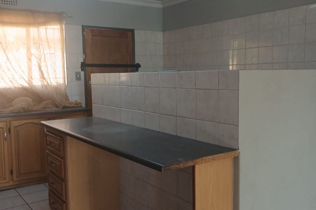 A dated kitchen area featuring tiled flooring, built-in cabinetry, and a tiled splashback, offering a functional layout ready for modernization.