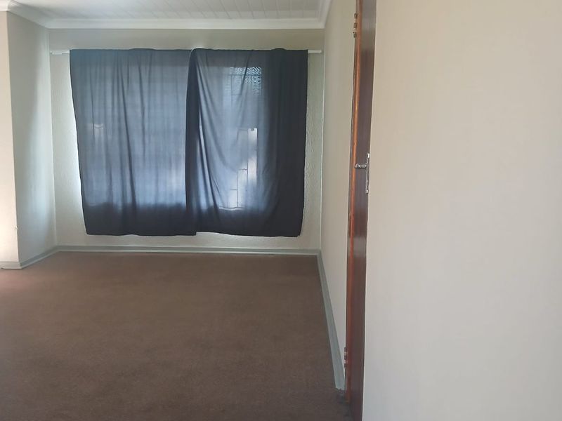 An empty bedroom featuring carpeted flooring, a tongue and groove ceiling, and a wooden door.