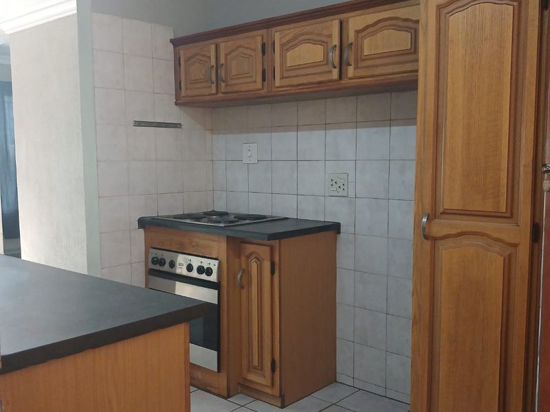 A functional kitchen featuring built-in wooden cabinetry, a built-in oven with hob, tiled backsplash, and tiled flooring.
