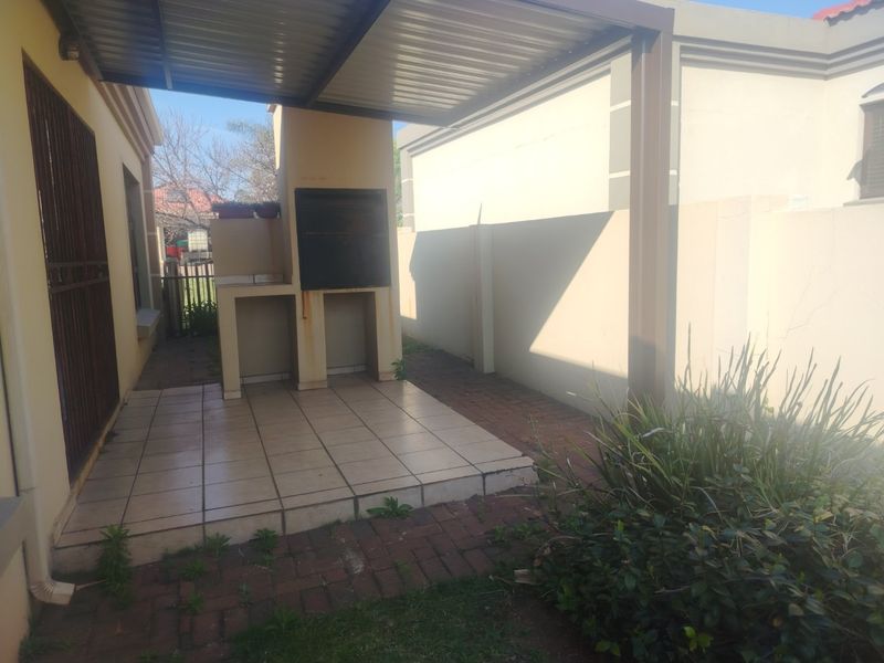 A covered outdoor patio area featuring a built-in braai, tiled flooring, and paved surrounds, offering a functional space for outdoor entertaining.