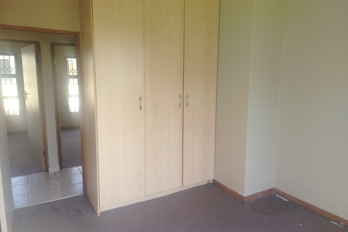 A vacant bedroom featuring built-in cupboards, neutral wall finishes, and carpeted flooring, providing a blank canvas for personalization.