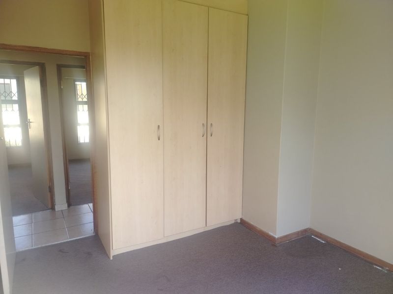 A vacant bedroom featuring built-in cupboards, neutral wall finishes, and carpeted flooring, providing a blank canvas for personalization.