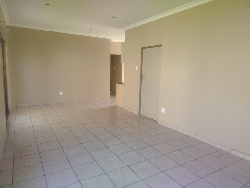 Spacious open-plan living area featuring neutral wall tones, tiled flooring, and recessed downlighting, offering a versatile blank canvas for interior design.