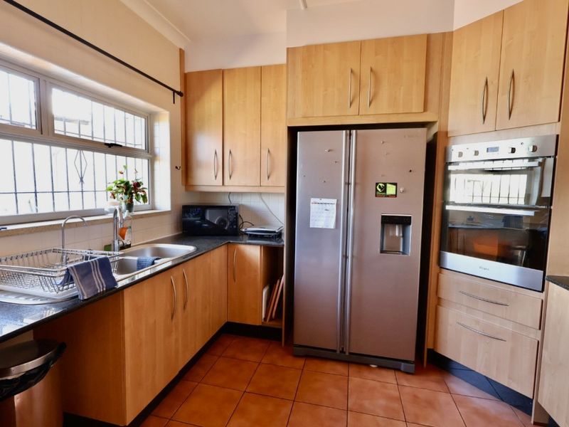 A functional kitchen featuring light wood cabinetry, dark countertops, tiled flooring, and a built-in oven, offering a practical layout for daily meal preparation.