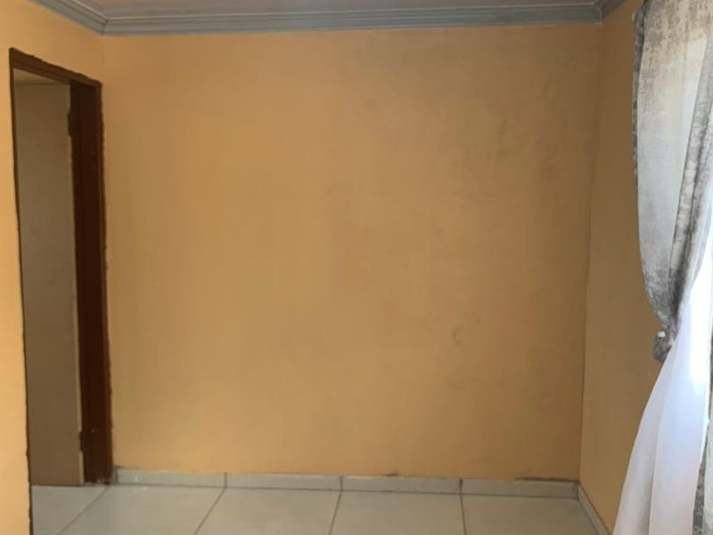 An empty bedroom featuring tiled flooring, neutral wall paint, and a simple ceiling light fixture, ready for personalization.