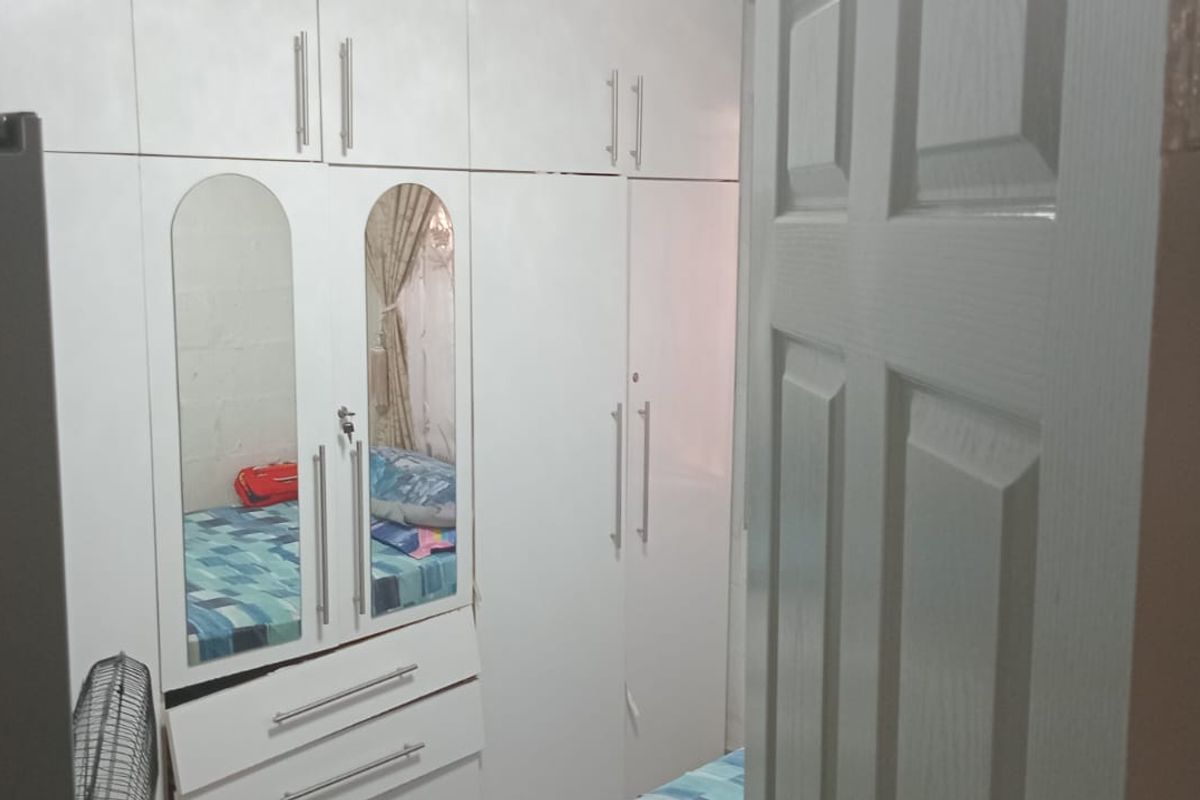 A bedroom featuring white built-in cupboards with integrated mirrored doors, providing ample storage space.