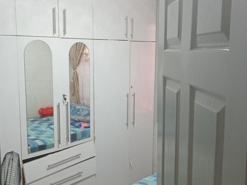 A bedroom featuring white built-in cupboards with integrated mirrored doors, providing ample storage space.