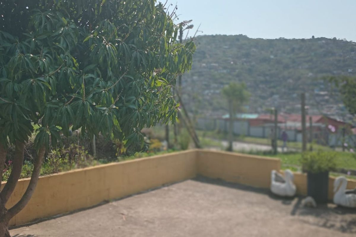 An outdoor concrete patio area featuring a low retaining wall and views of the surrounding neighborhood.