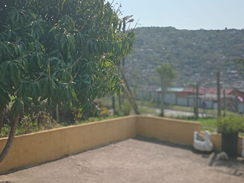 An outdoor concrete patio area featuring a low retaining wall and views of the surrounding neighborhood.
