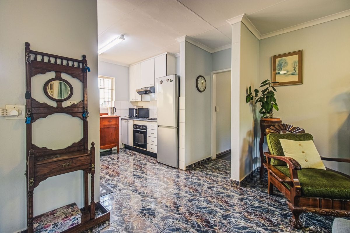 A functional kitchen area featuring built-in cabinetry, integrated oven and hob, and distinctive tiled flooring, connecting to an adjacent living space.
