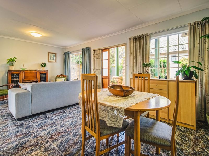 Open-plan living and dining area featuring tiled flooring, large windows, and sliding door access to the outdoor patio space.