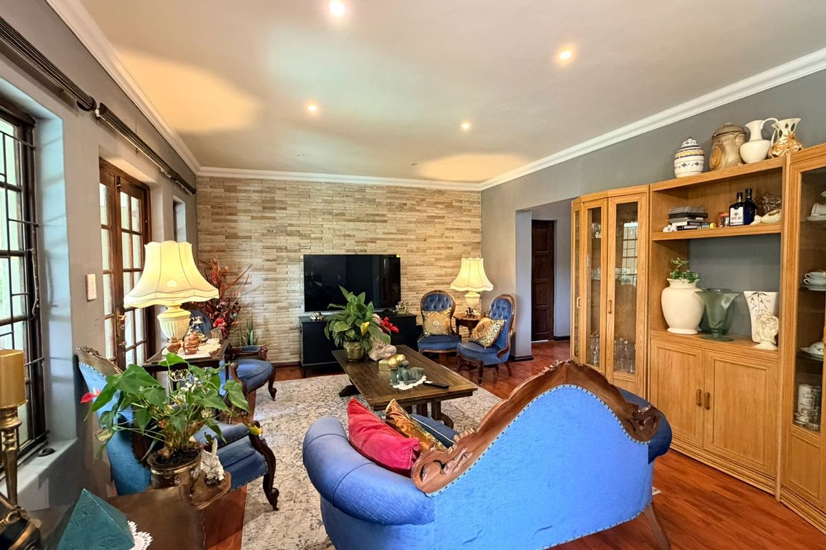 Spacious living room featuring hardwood flooring, a textured stone feature wall, recessed lighting, and built-in wooden cabinetry.