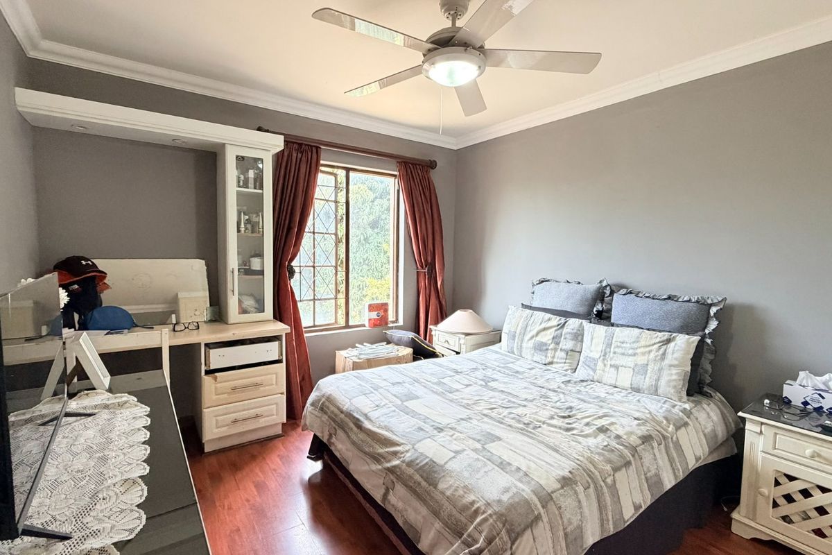 A well-proportioned bedroom featuring laminate flooring, a ceiling fan, and integrated built-in cabinetry with a desk area.