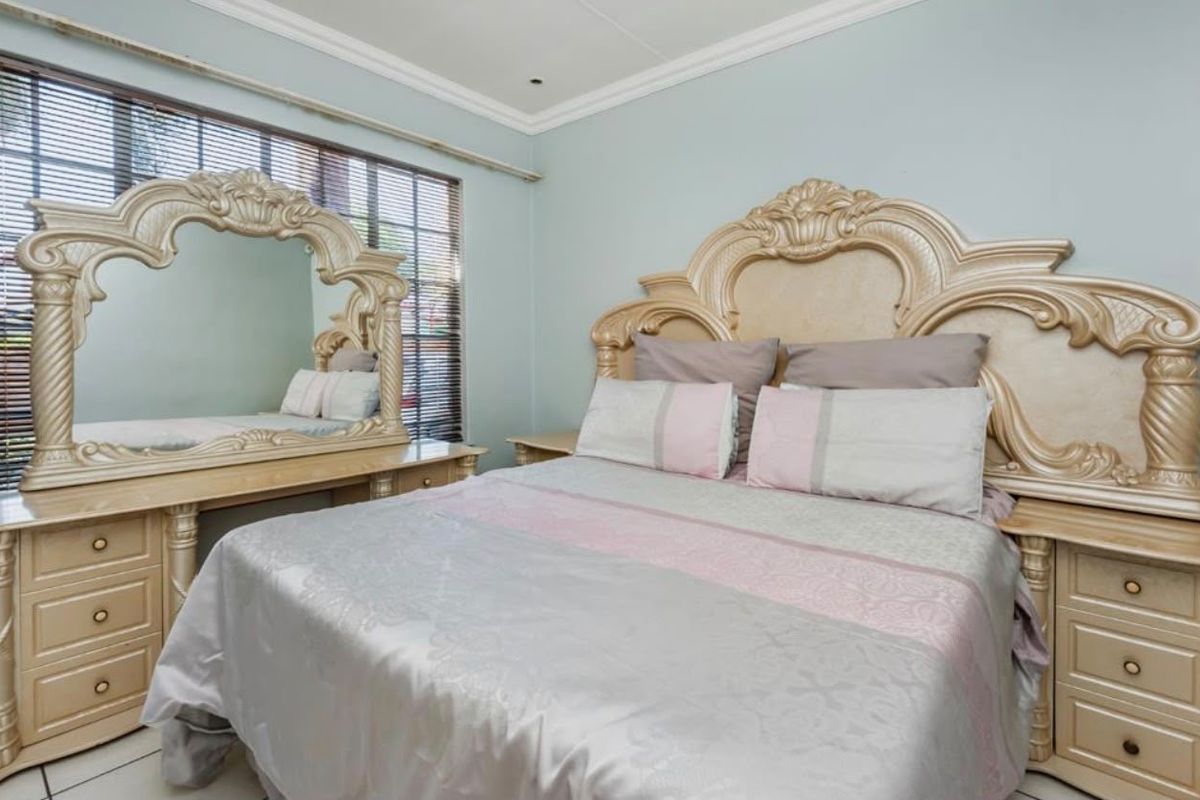 A well-maintained bedroom featuring crown molding and venetian blinds, offering a neutral base for potential interior updates.